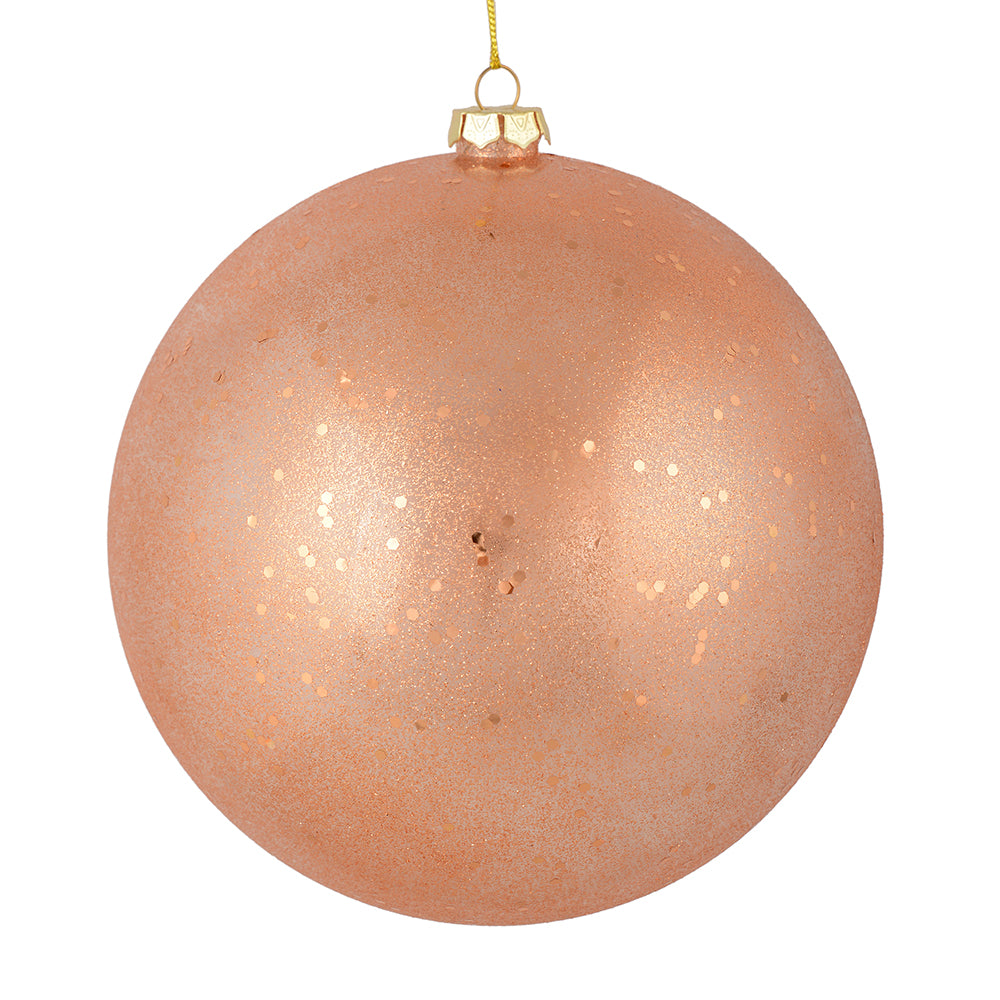 Vickerman 6" Rose Gold Glitter Clear Ball. This ornament features a clear complexion with a dusting of rose gold glitter inside. Add a touch of glam to any holiday arrangement with this delicate looking ornament. Made with shatterproof plastic. Includes 4